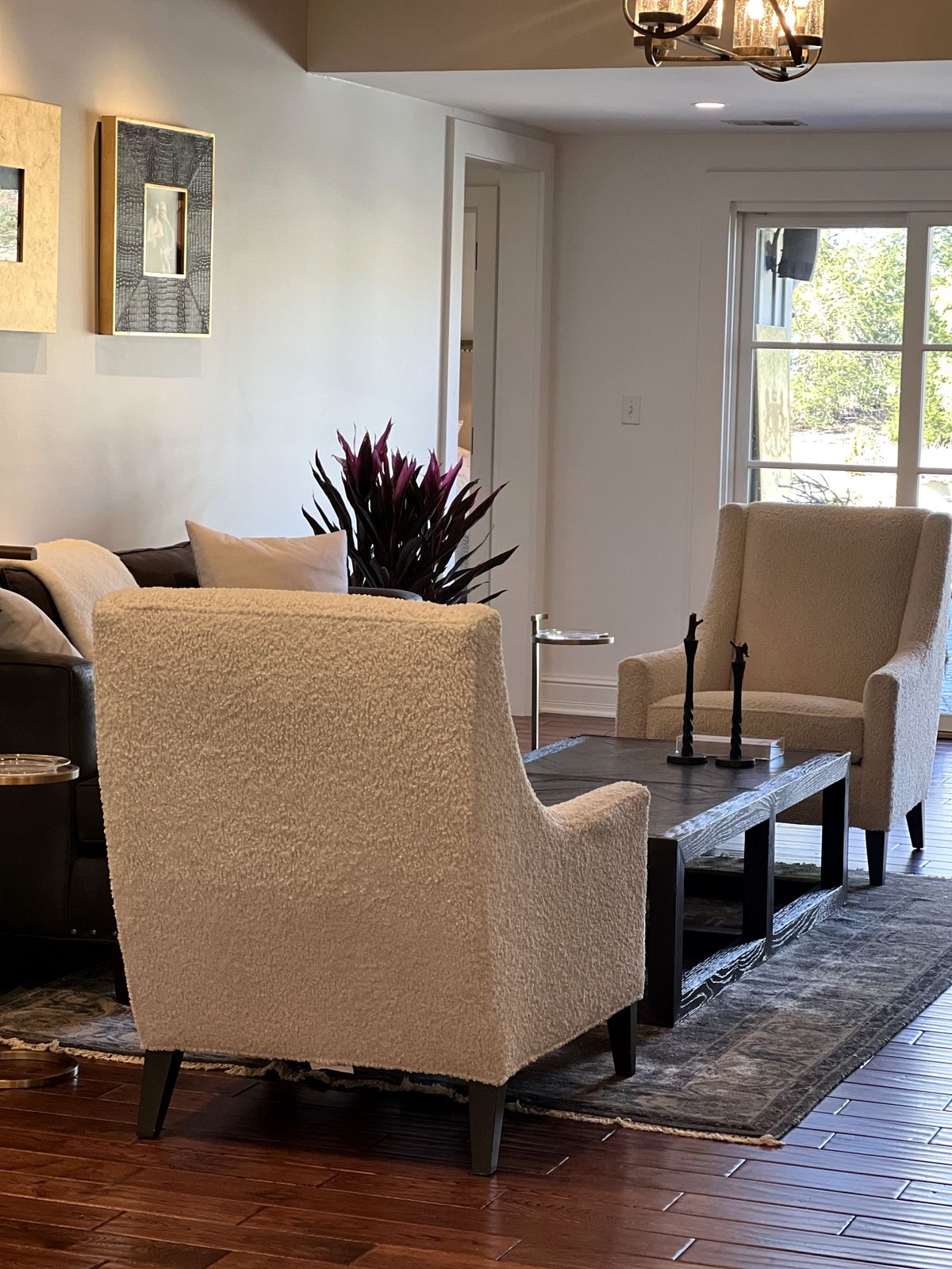 Two cream bouclé armchairs around a dark wood coffee table
