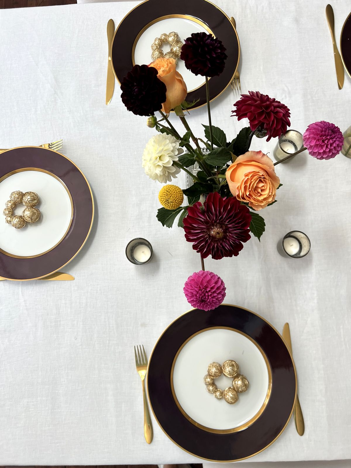 Dinner table with plum and gold plates and dahlias