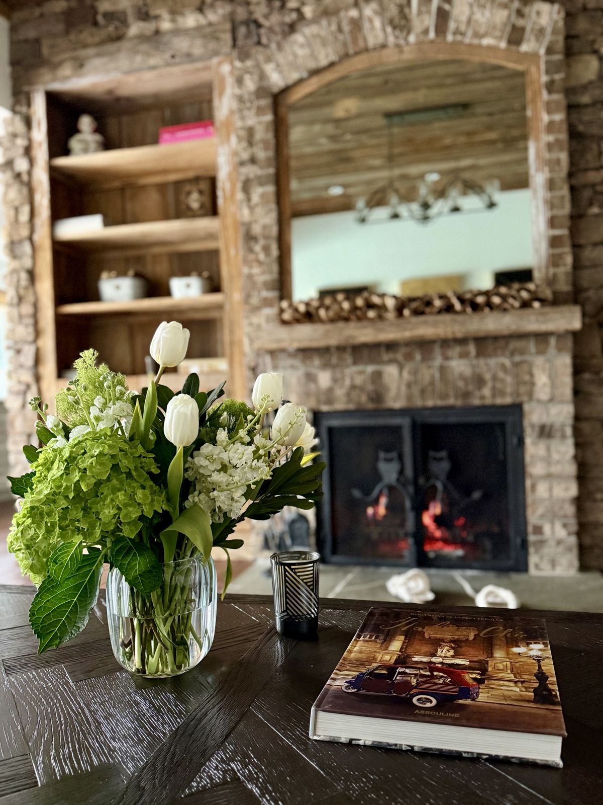 White tulips and green hydrangea on a coffee table by the fireplace